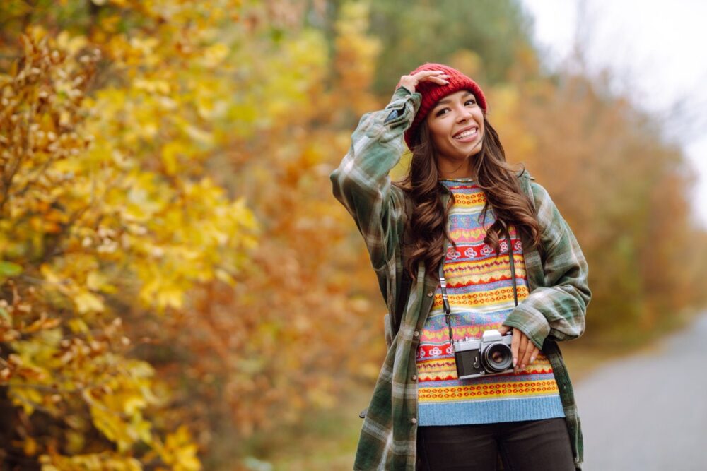 امرأة شابة جميلة تُلتقط لها صورة بكاميرا عتيقة. مفهوم الراحة، الاسترخاء، السفر، ونمط الحياة